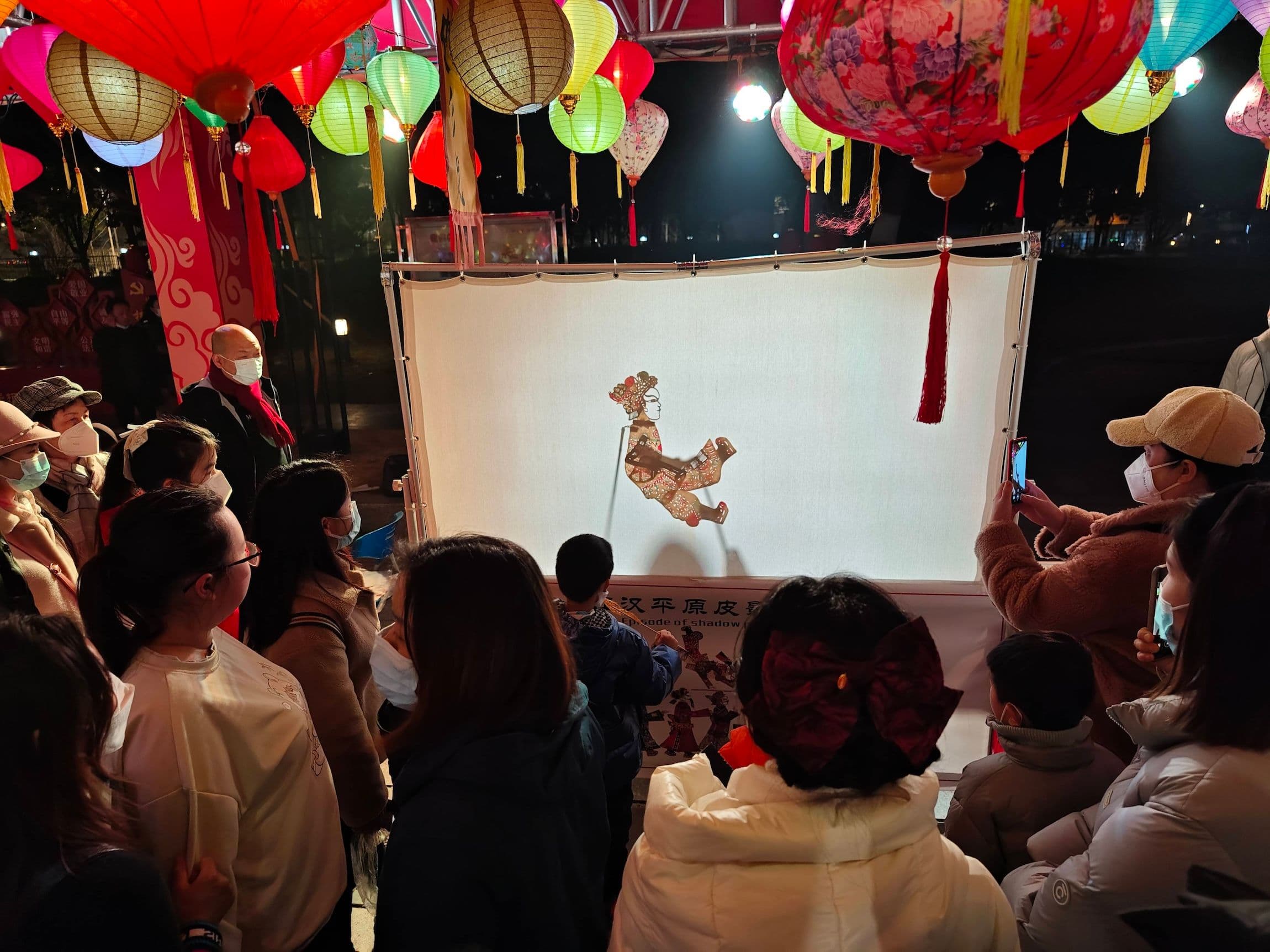 Ein Kind erlebt das chinesische Schattenspiel auf einem Nachtmarkt des immateriellen Kulturerbes im Museum der Provinz Hubei