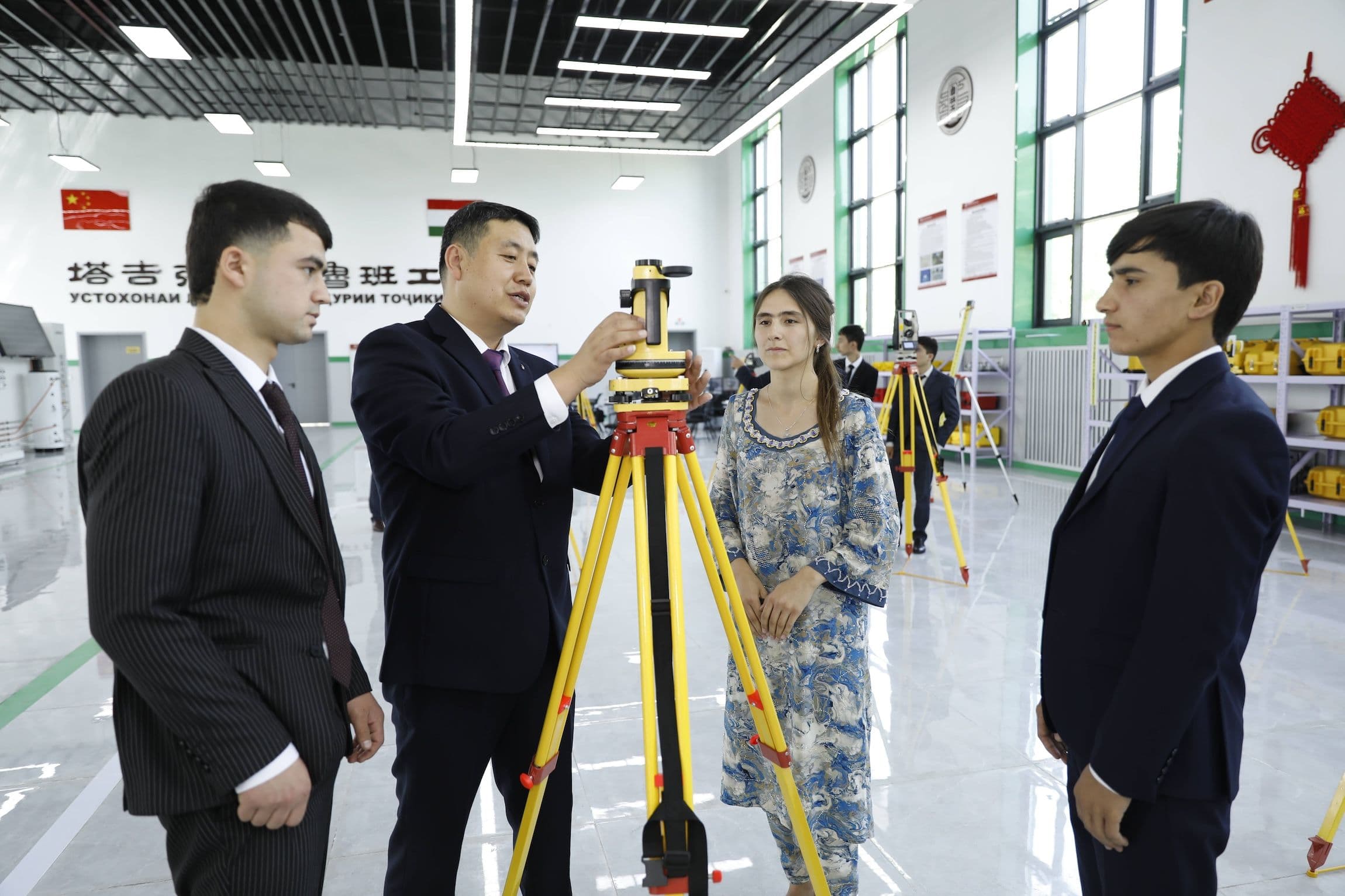 ein Lehrer vom Tianjin Urban Construction Management & Vocation Technology College, führt Schüler beim Luban-Workshop in Tadschikistan in die Verwendung von Kartierungsgeräten ein