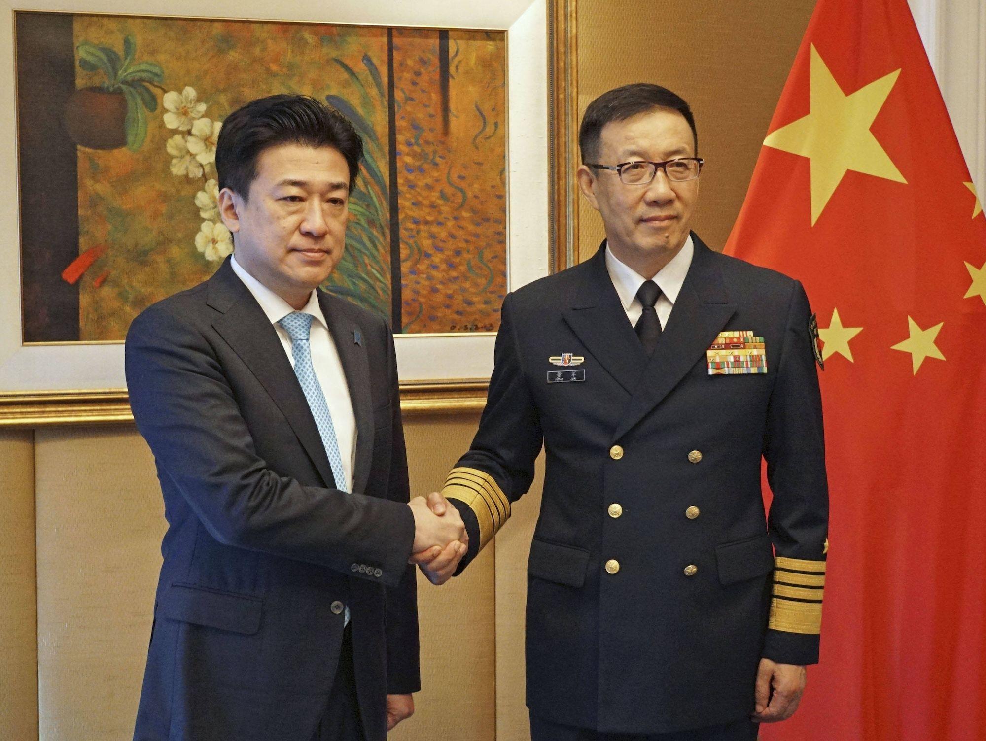 Der japanische Verteidigungsminister Minoru Kihara (L) schüttelt seinem chinesischen Amtskollegen Dong Jun während eines Treffens in Singapur die Hand