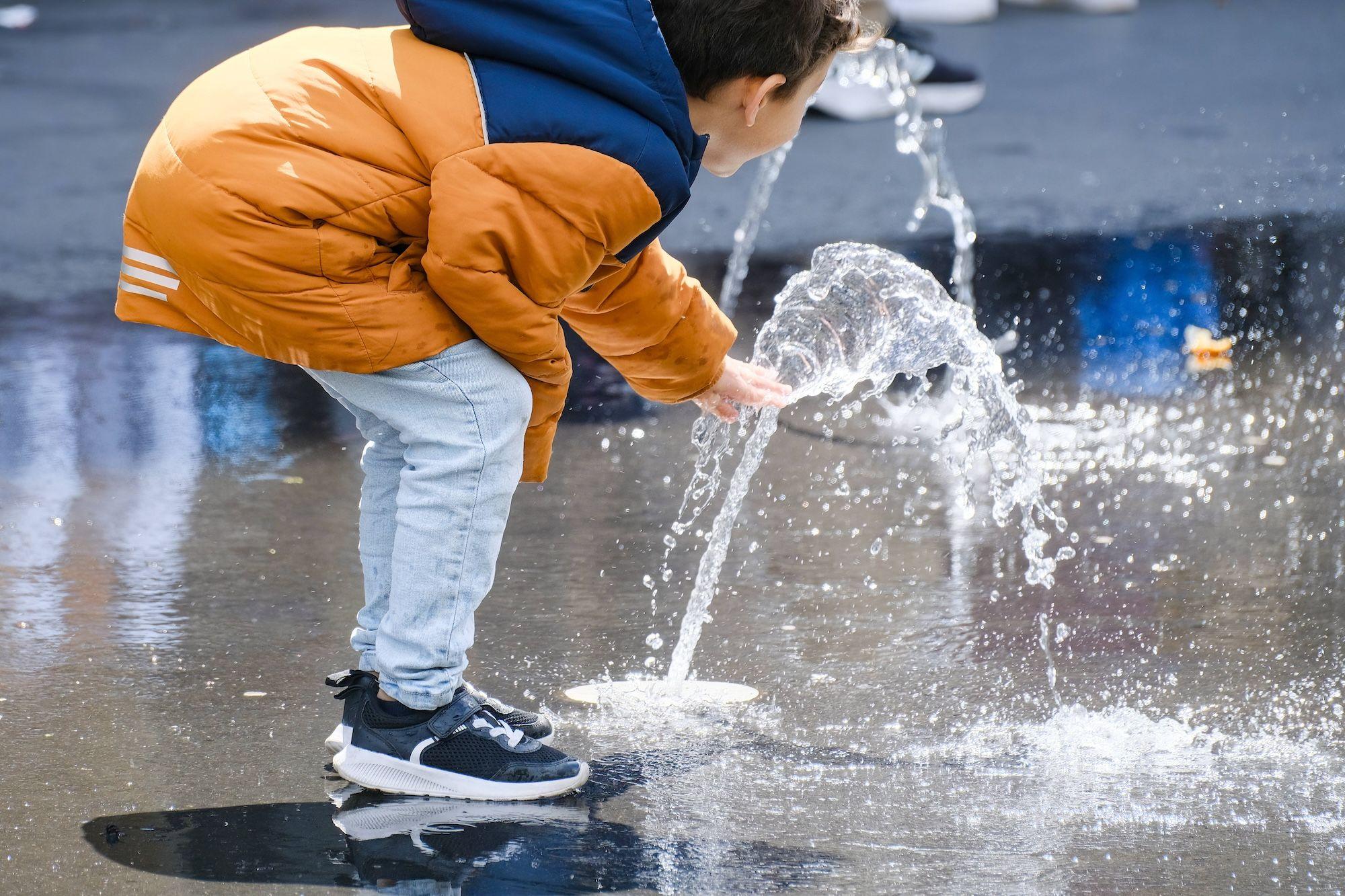 Ein Kind spielt in Brunnen mit Wasser. China News. China EU Kooperation. Trinkwasser. sichere Wasserversorgung