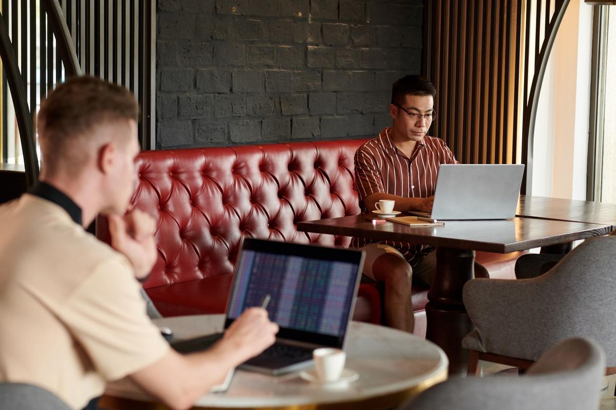 Händler arbeitet am Laptop in einem Café und analysiert Aktien und Weltnachrichten. China News, Aktienkurse in Asien, Asiatischer Aktienmarkt