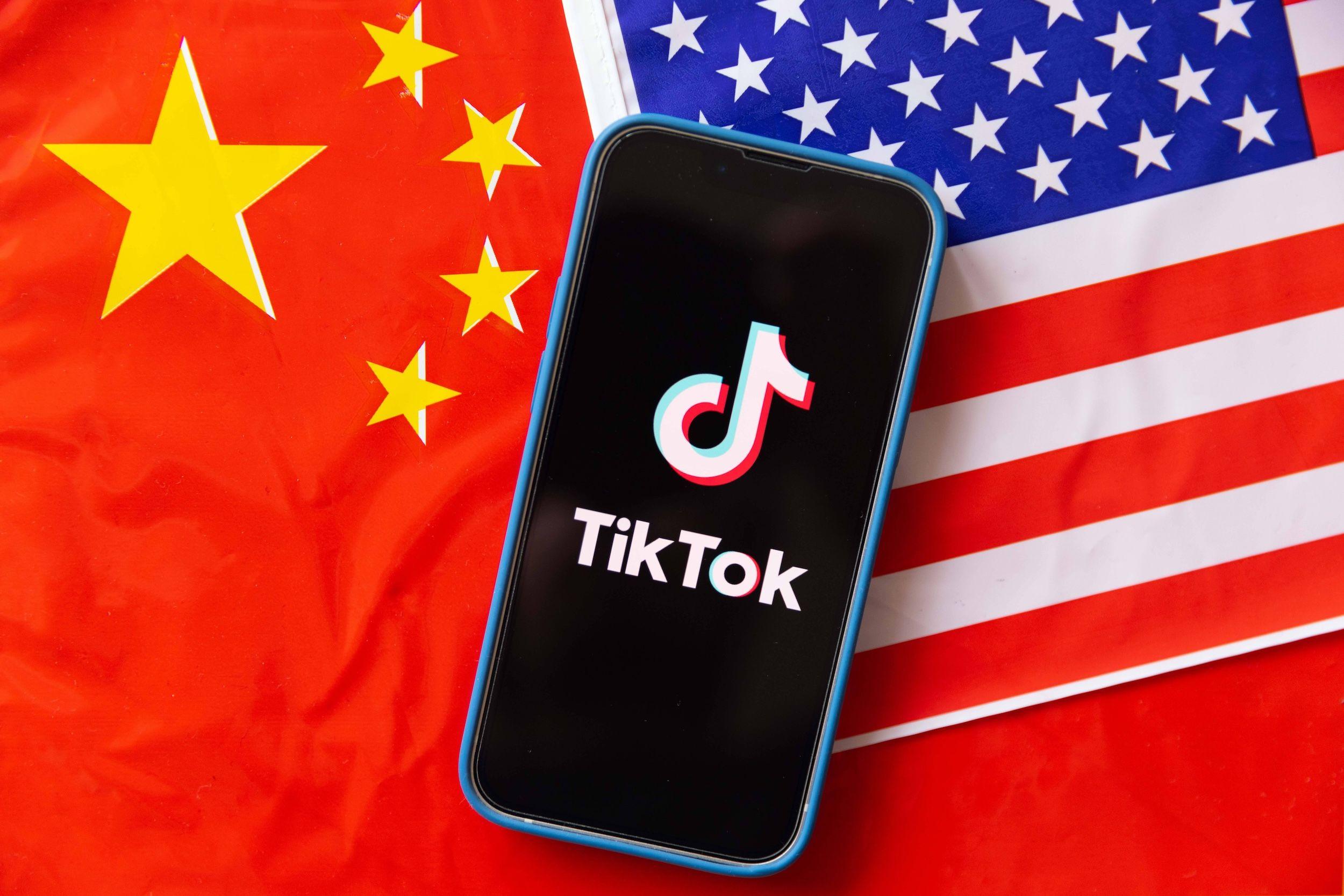 Das Mobiltelefon zeigt das TikTok-Logo mit den Flaggen der Vereinigten Staaten von Amerika und der Volksrepublik China.